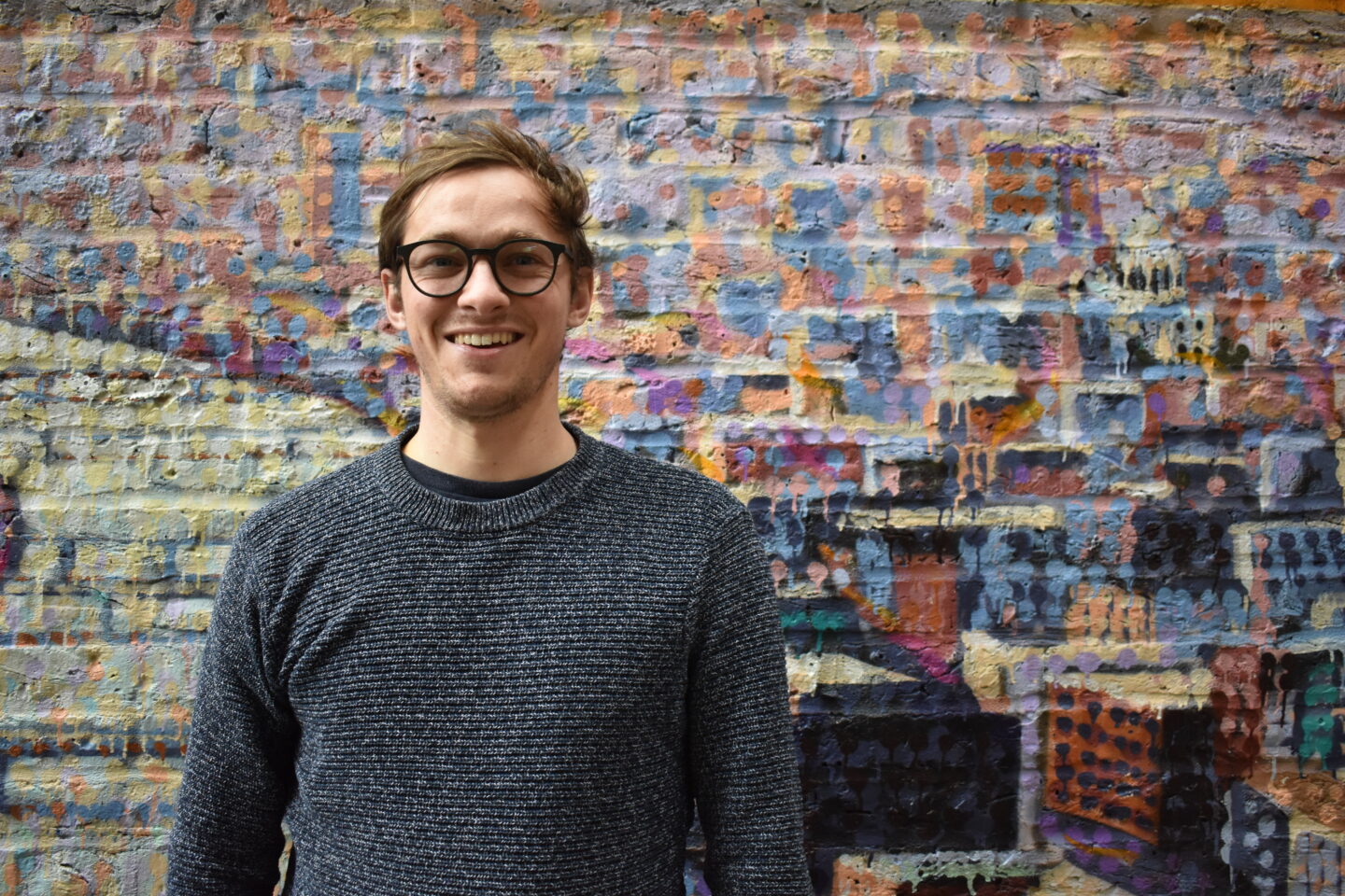 Rory, Paper Round's Head of Sustainability standing in front of graffiti in central London